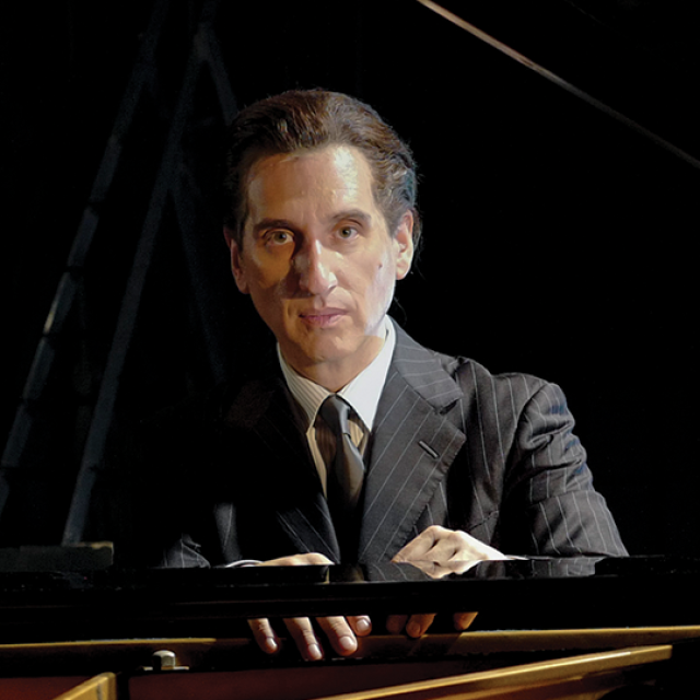 Hershey Felder, pianist, looks into the camera while seated at the piano.