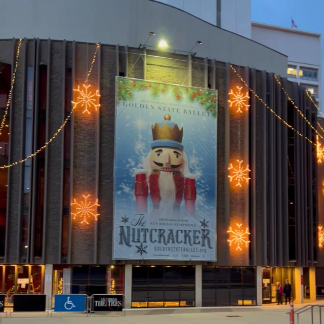 Facade of Civic Theatre with large light-up snowflakes and banner promoting The Nutcracker, complete with image of nutcracker, snow, holly, and text sharing show information from 2023.