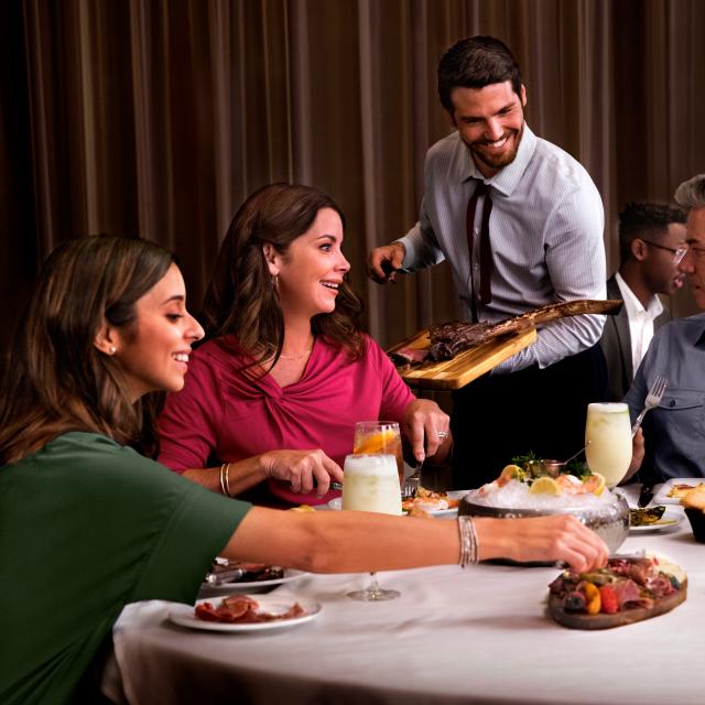 Family Dining in restaurant while being served by chef