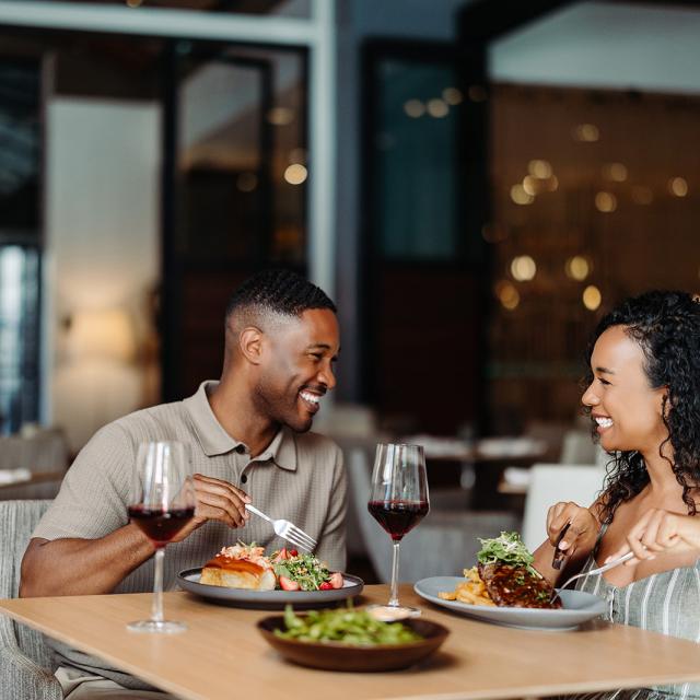 two people sitting at a table with food and drinks 