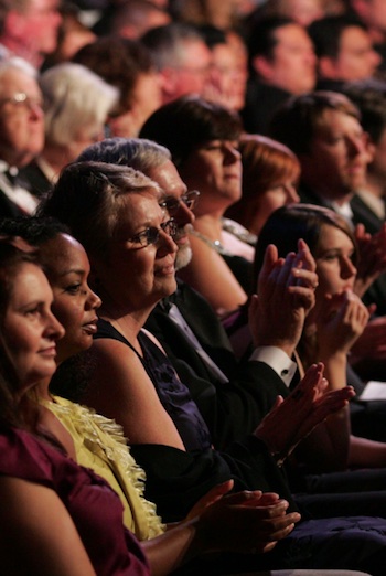 Side portrait of formal theatre patrons watching a show with smiles on their faces