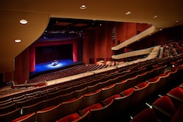 Photo of the San Diego Civic Theatre stage, with empty seats in the foreground and a grand piano on stage